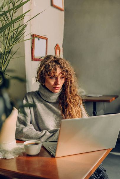 Młoda kobieta freelancer pracuje w kawiarni za pomocą laptopa i smartfona. Skupienie selektywne. - Zdjęcie, obraz