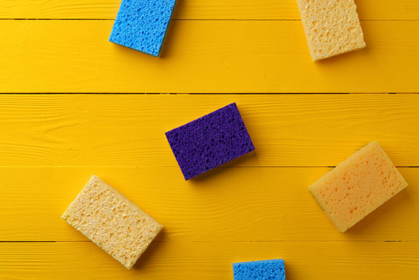 Cleaning sponges on yellow wooden background flat lay - Foto, Bild