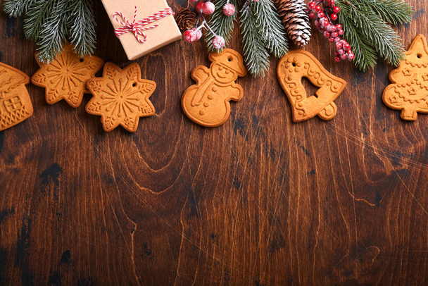 Christmas fir tree branches, Christmas balls, Christmas gingerbread, gift box, wooden snowflakes and stars on old wooden background for xmas greetings. Top view, copy space. Christmas greeting card. - Φωτογραφία, εικόνα