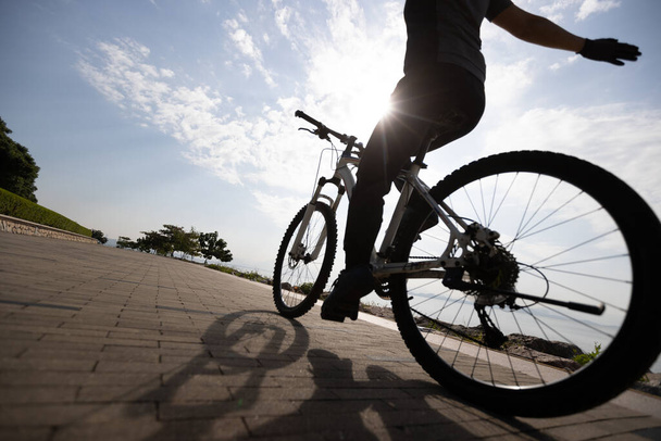 Montar en bicicleta sin sostener el manillar en el camino de la costa del amanecer - Foto, imagen