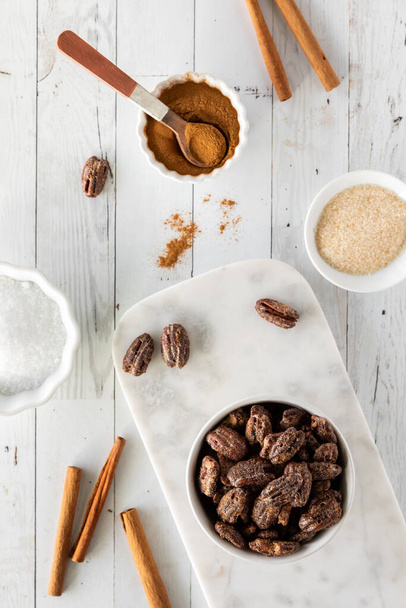 Top down view of a bowl of candied pecans surrounded by ingredients to make them - Photo, Image
