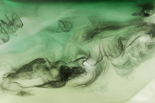 Green smoke on black ink background, colorful fog, abstract swirling emerald ocean sea, acrylic paint pigment underwater - Photo, Image