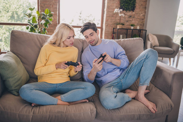 Portrait of handsome beautiful couple sitting on divan playing game learning at home loft industrial interior indoors - Photo, Image