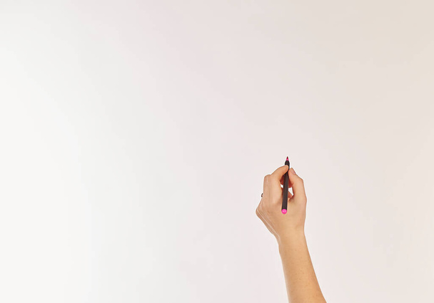 Una mano femenina está lista para dibujar con un marcador negro. Aislado sobre blanco. El marcador escribe en rojo. - Foto, Imagen