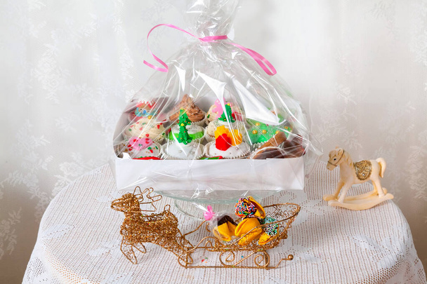 Dárková krabice s domácími koláčky, košíčky, muffiny zdobené ve vánočním stylu. Sezónní slavnostní vánoční mini zákusky v tradičních dekorativních symbolů prvků - Fotografie, Obrázek