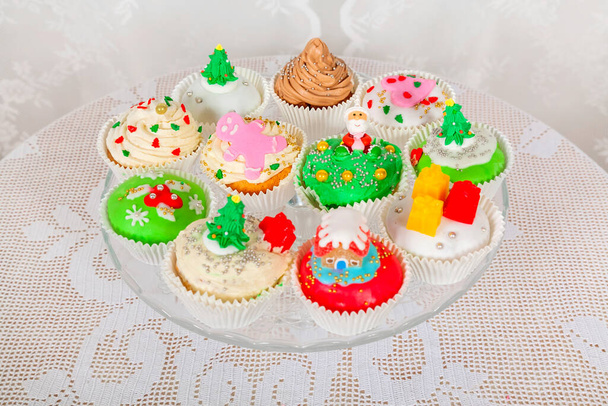 Un support en verre avec des gâteaux faits maison, des cupcakes, des muffins décorés dans un style de Noël. Petits gâteaux de Noël festifs saisonniers en symboles décoratifs traditionnels éléments - Photo, image