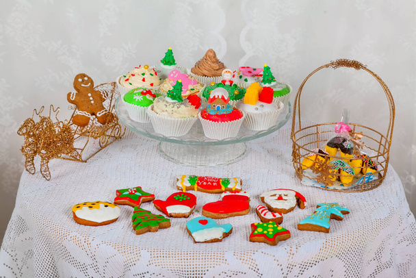 Presentes doces com bolos caseiros, cupcakes, muffins e biscoitos de gengibre decorados em estilo natalino. Natal festivo sazonal mini sobremesa cupcakes em elementos de símbolos decorativos tradicionais - Foto, Imagem