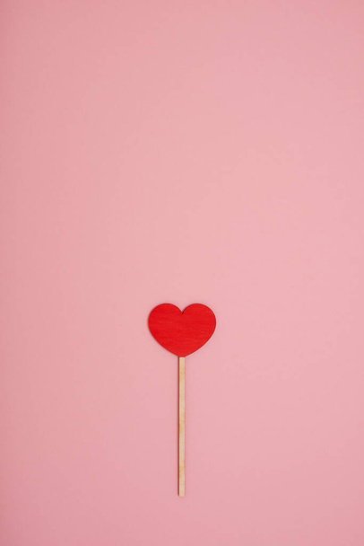 Red wooden love heart on a pink pastel background - Foto, afbeelding