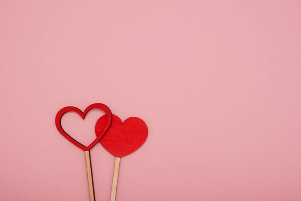 Twee rode houten liefdesharten op een roze achtergrond - Foto, afbeelding