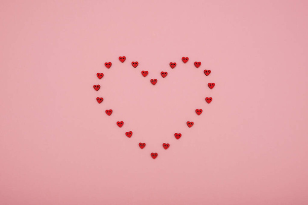 Valentine's Day heart shape made of small red hearts on a pink background - Foto, afbeelding