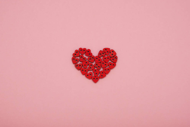 Valentine's Day heart made of small red wooden hearts on a pink background - Φωτογραφία, εικόνα