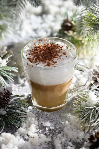 Christmas latte macchiato. A great hot coffee drink with chocolate shavings, among the snow-covered pine branches and snow. - Foto, imagen
