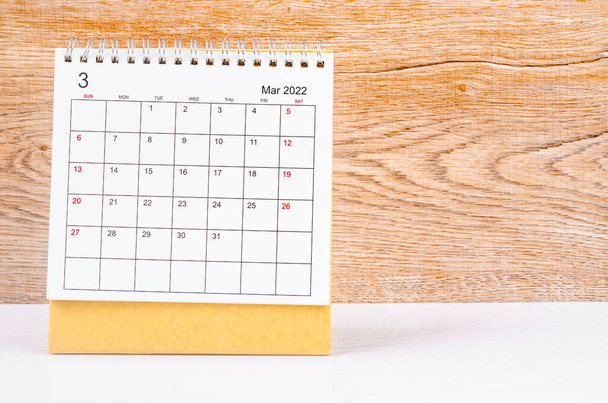 The March 2022 desk calendar on wooden table. - Φωτογραφία, εικόνα