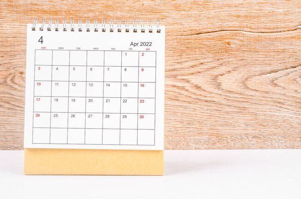 The april 2022 desk calendar on wooden table. - Foto, imagen