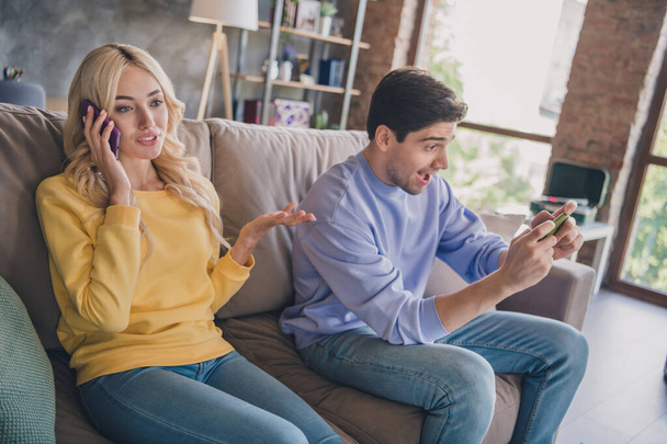 Portrait of attractive cheery couple sitting on divan using device chatting free time at home loft industrial interior indoors - Fotoğraf, Görsel