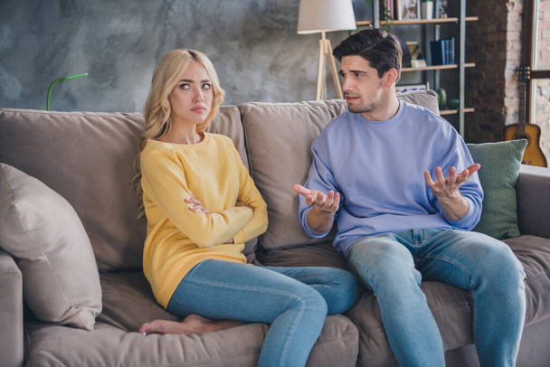 Photo of young couple unhappy negative moody conflict quarrel argument offended speak sit sofa indoors - Fotoğraf, Görsel