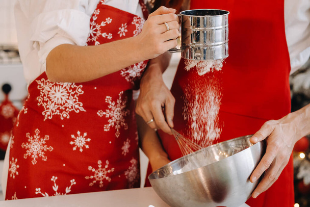 Close-up of hands pouring flour into a container for stirring dough. - Fotoğraf, Görsel