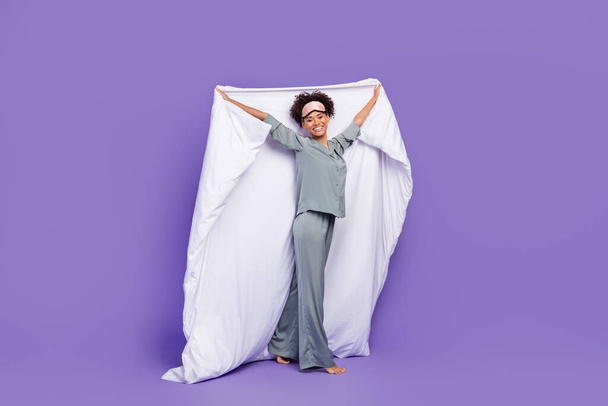 Photo shiny pretty african lady grey nightwear smiling rising blanket isolated purple color background - Foto, imagen