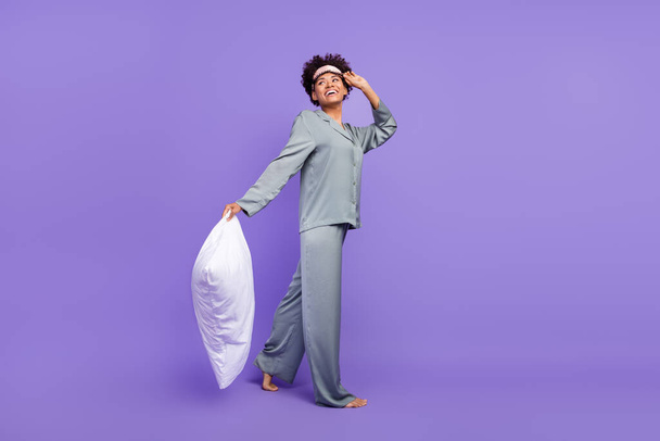Photo of adorable funny woman grey sleepwear smiling holding pillow walking looking empty space isolated violet color background. - Φωτογραφία, εικόνα