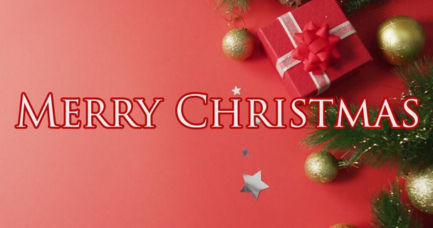 Image of merry christmas and decorations over red background with present. christmas, tradition and celebration concept digitally generated image. - Φωτογραφία, εικόνα