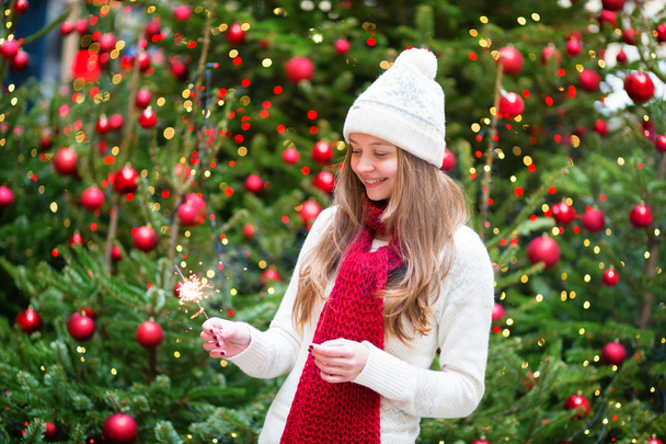 Girl with a sparkler near brightly Christmas tree - Photo, image