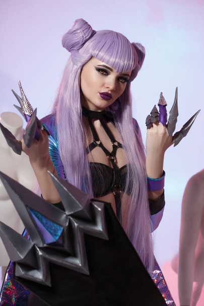 A cute girl witch with long purple hair with knife-claws on a bright blue and lilac background. - Foto, immagini
