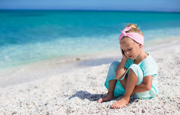 Little adorable girl talking at phone during beach vacation - Photo, Image