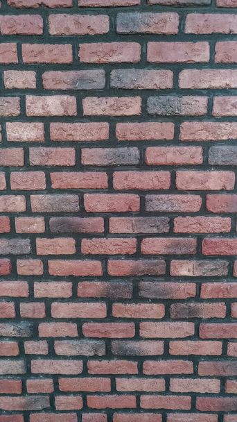 Une section verticale d'un vieux mur de briques peint en noir et rouge. - Photo, image