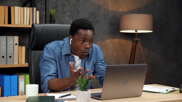 Возбужденный афроамериканец смотрит на ноутбук и отмечает рост финансового рынка - Кадры, видео
