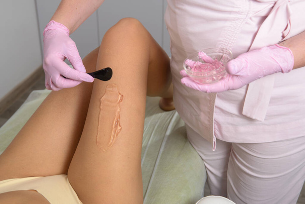 femme esthéticienne applique un gel de contact sur la jambe d'une femme pour l'épilation au laser dans une clinique médicale. Gros plan - Photo, image