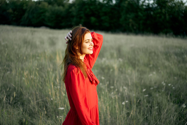 όμορφη γυναίκα σε κόκκινο φόρεμα στο πεδίο φύση θέτοντας τοπίο - Φωτογραφία, εικόνα