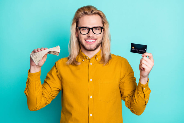 Photo of young business man happy positive smile hold credit card cash money rich isolated over teal color background. - Фото, изображение