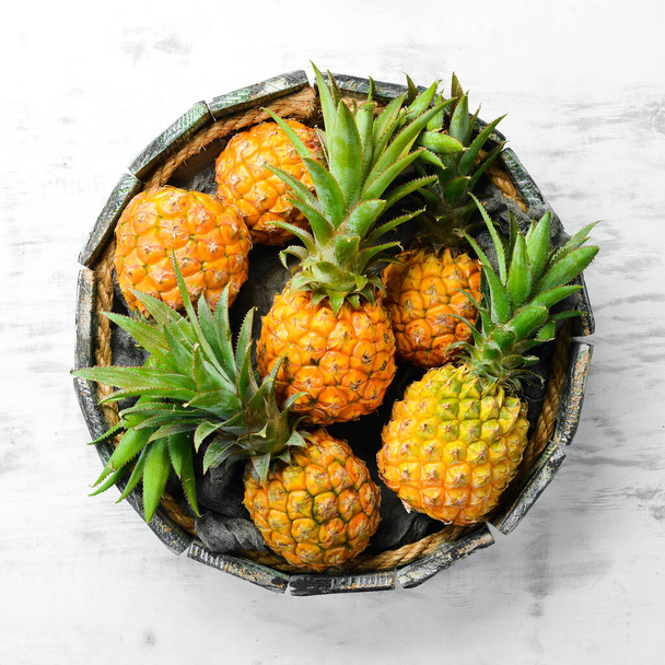 Pineapples in a wooden box. Ripe baby pineapple. Tropical fruits. Top view. Free space for text. - Foto, Imagem