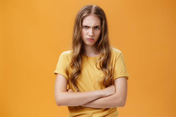 Girl mad like devil. Portrait of angry bothered and offended hateful young woman looking from under forehead frowning and sulking crossing arms against chest in defensive pose, scorning offender - Фото, изображение