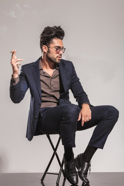 side of a seated man in suit and glasses smoking - Foto, immagini