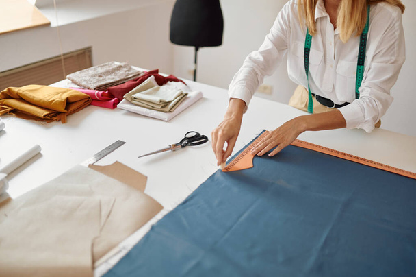Dressmaker measures cloth at workplace in workshop - Fotó, kép