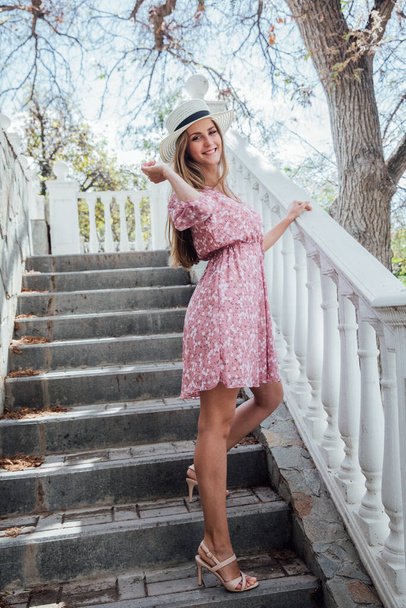 kaunis muodikas blondi nainen hattu ja vaaleanpunainen mekko portaissa - Valokuva, kuva