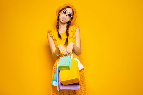 cheerful woman with multicolored bags posing yellow background - 写真・画像