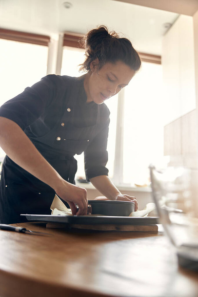 joven cocinera profesional está preparando sabroso pastel en su cocina moderna luz - Foto, imagen
