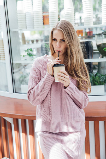 belle femme blonde à la mode en vêtements roses boire un cocktail de café - Photo, image