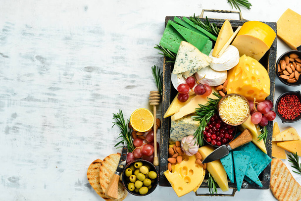 Set of cheeses with snacks in a wooden box. On a white wooden background. Free copy space. - Valokuva, kuva