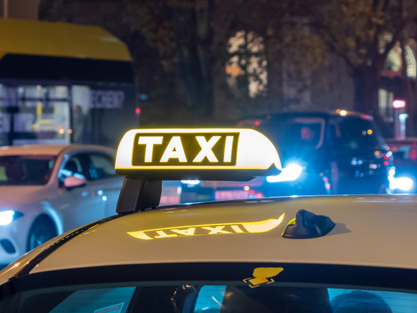 Fotografia notturna di un taxi. Taxi segno sul tetto dell'auto brilla nel dar - Foto, immagini