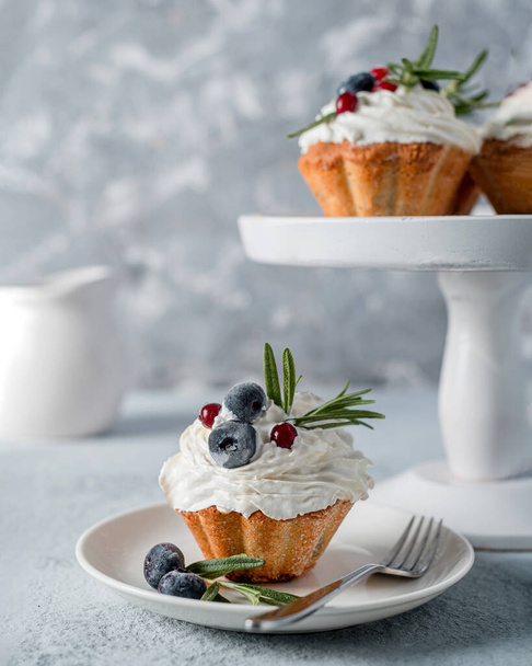 Cupcake (muffin) with blueberry and rosemary butter cream on a gray photo. High key, homemade baked goods - Foto, Imagen