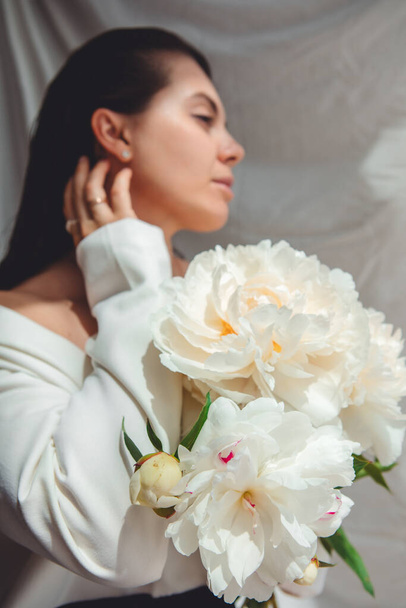 mooie prachtige vrouw met pioenrozen bloemen. close-up - Foto, afbeelding