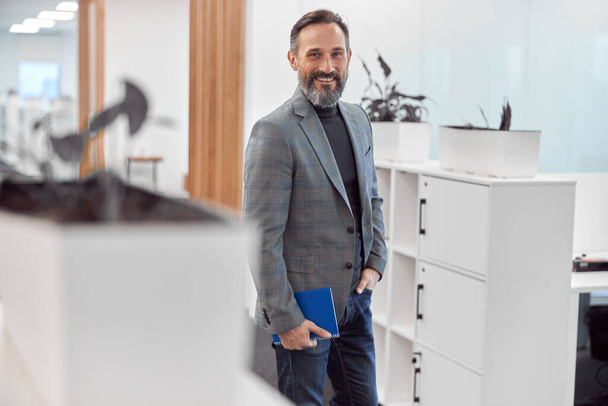 Slimme mannelijke kantoormedewerker loopt in een modern kantoor - Foto, afbeelding