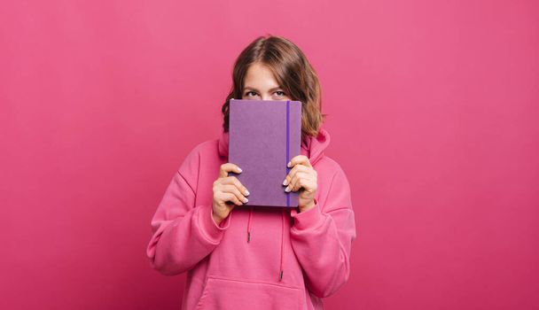 Foto de una joven de color rosa sosteniendo su nuevo planificador de agenda para 2022 año - Foto, Imagen
