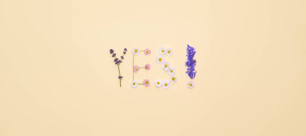 Word "YES" made of flowers on bright yellow background. Summer concept. Flat lay top view - Fotó, kép