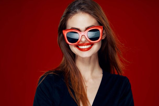 csinos nő visel napszemüveg divat pózol frizura piros háttér - Fotó, kép