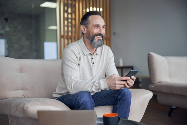 Boldog felnőtt férfi üzletember ül és hűvös hangulatos irodahelyiségben - Fotó, kép