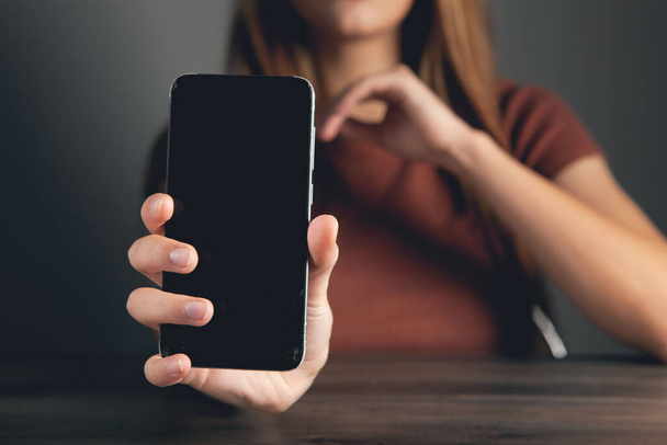 young woman shows phone on gray background - Fotoğraf, Görsel